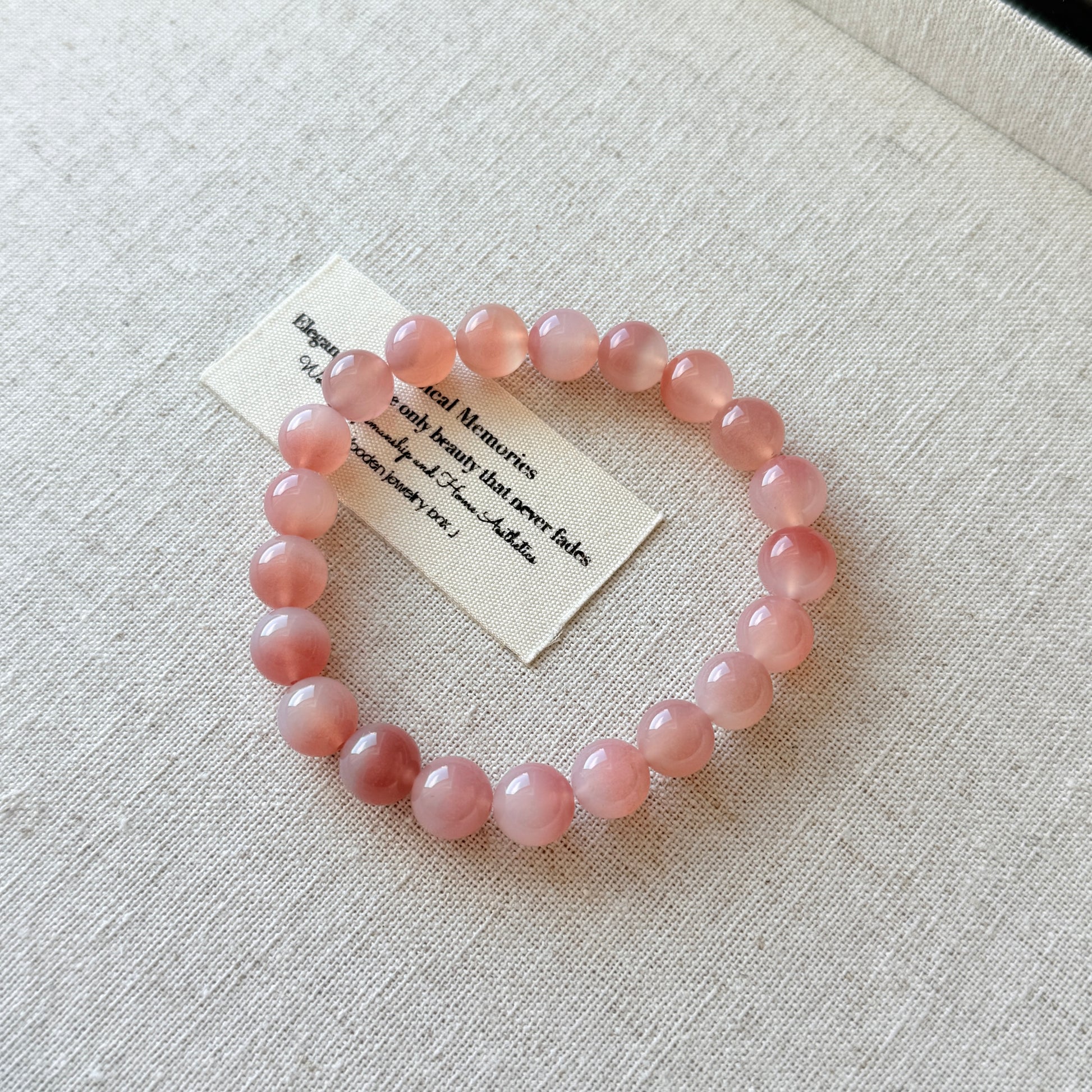 Pink beaded bracelet on a light gray fabric background