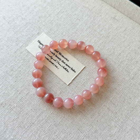 Pink beaded bracelet on a light gray fabric background